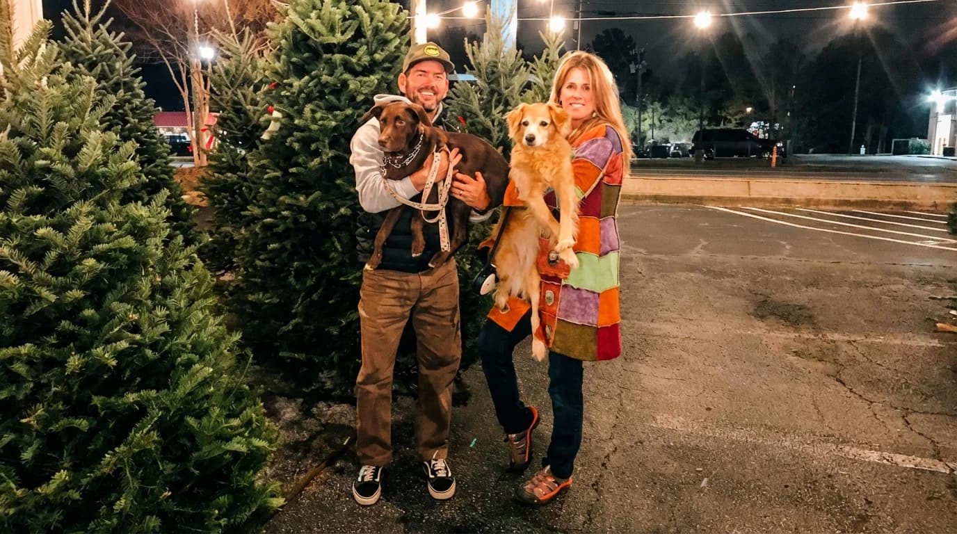 Frank and his wife holding their dogs at a Christmas tree lot